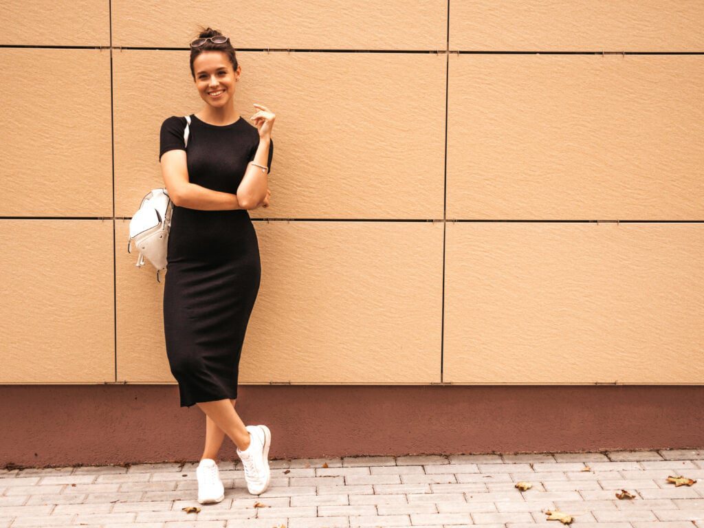 Dress hitam dengan sneakers menciptakan gaya santai tapi tetap stylish. 